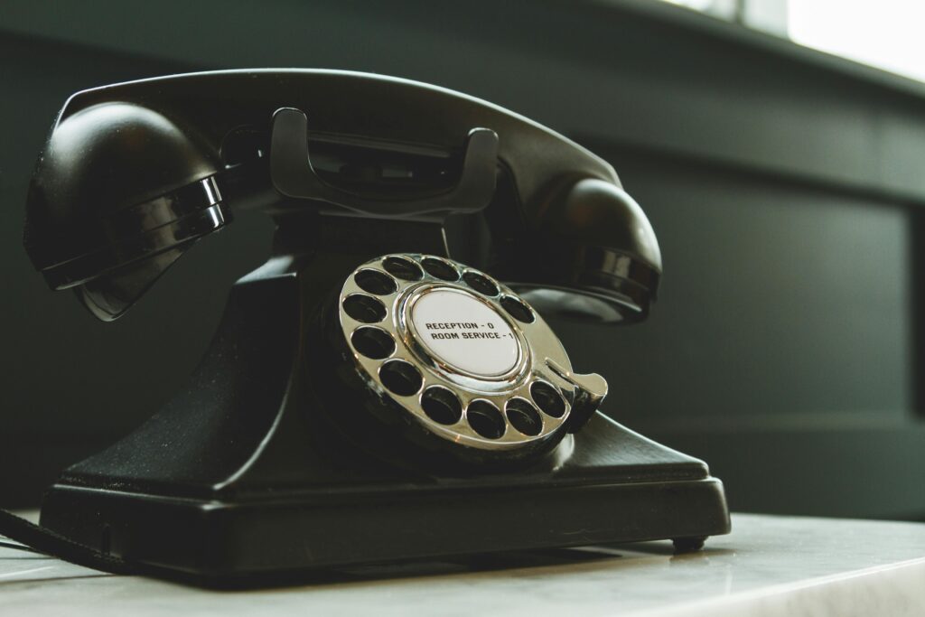 pexels-photo-1416530-1416530 Classic black rotary phone on hotel reception desk, evoking nostalgia and vintage charm.