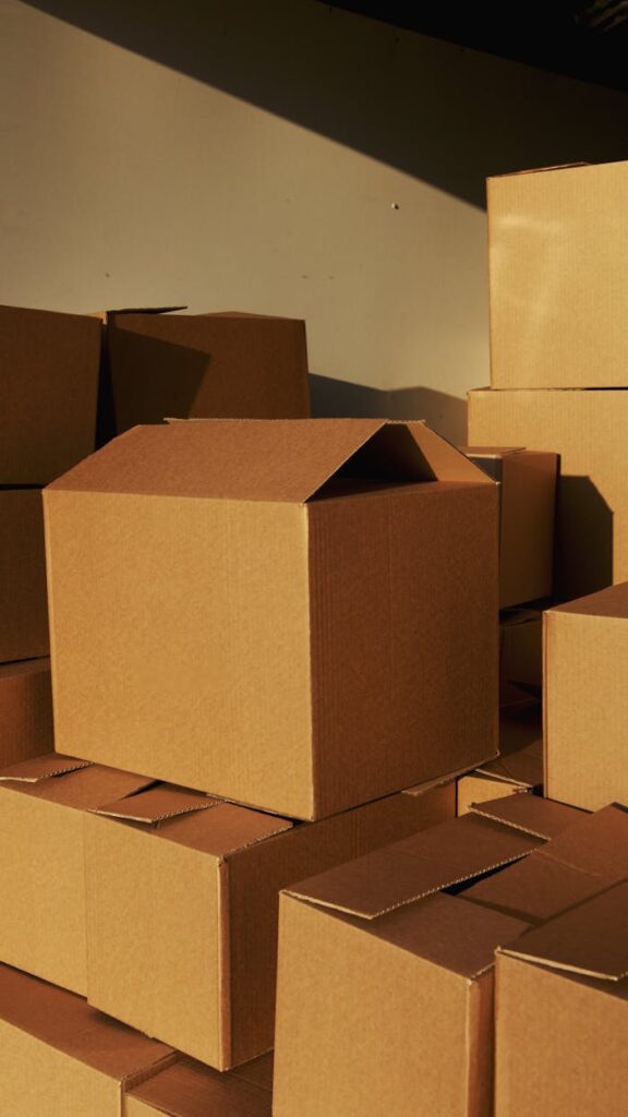 pexels-photo-5025503 Stacked cardboard boxes ready for shipping or storage in a warehouse setting.